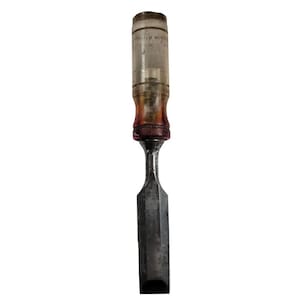 May include: A vintage chisel with a clear, cylindrical handle and a metal blade. The handle shows signs of wear and age, with a reddish-brown band near the blade. The blade is rectangular and appears well-used.