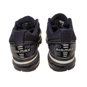May include: Pair of black and gray Airmax athletic shoes. The shoes have a black upper with gray accents and a white midsole. The Airmax logo is visible on the heel.