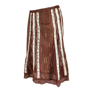 Peut inclure: Une jupe marron avec des bordures en dentelle blanche et des accents dor&eacute;s. La jupe a une silhouette fluide et &eacute;vas&eacute;e.