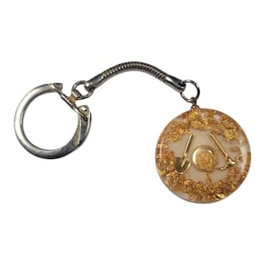 May include: A silver keychain with a circular pendant. The pendant is filled with gold flakes and features gold-colored tools, including a shovel and pickaxe. The keychain has a flexible, coiled connector.