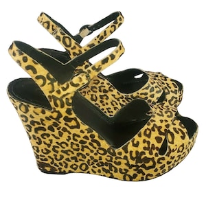 May include: A pair of leopard print wedge sandals with a black platform and ankle strap.