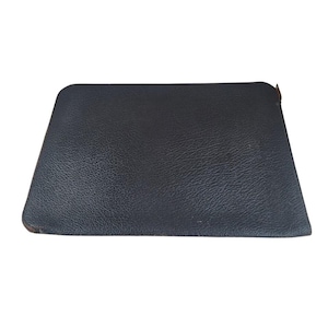 May include: A rectangular, black leather pouch with rounded corners. The pouch has a textured surface and a small, brown accent near the top right corner. The pouch is empty and sits on a white background.