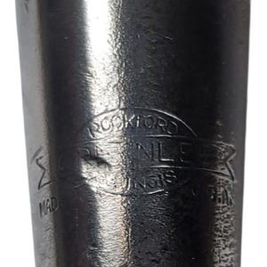 Puede incluir: Primer plano de un objeto de acero inoxidable con el texto "ROCKFORD STAINLESS UNGS" en un emblema circular. Tambi&eacute;n es visible la palabra "MADE".