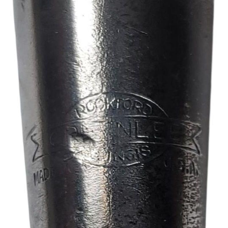 Puede incluir: Primer plano de un objeto de acero inoxidable con el texto "ROCKFORD STAINLESS UNGS" en un emblema circular. Tambi&eacute;n es visible la palabra "MADE".
