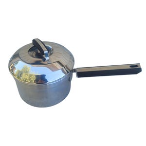 May include: A stainless steel saucepan with a polished finish, featuring a matching lid with a black handle. The pan has a long, straight black handle extending from the side, designed for stovetop cooking and kitchen utility tasks.