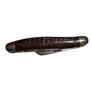 May include: A brown pocket knife with a wood handle and two blades. The knife has a rounded tip and a silver metal frame.