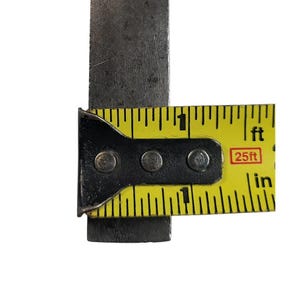 Puede incluir: Primer plano de una cinta m&eacute;trica amarilla y negra con un objeto met&aacute;lico. La cinta muestra medidas en pulgadas y pies, con el texto "25ft" visible. El objeto met&aacute;lico es de color gris oscuro y rectangular.