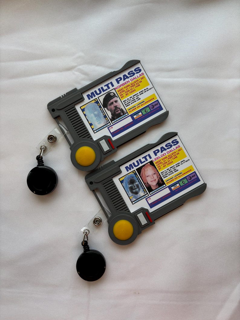 Puede incluir: Dos tarjetas multi-pass de pl&aacute;stico gris con una foto en blanco y negro de una persona en cada tarjeta. Las tarjetas tienen un bot&oacute;n amarillo y un cord&oacute;n retr&aacute;ctil negro.