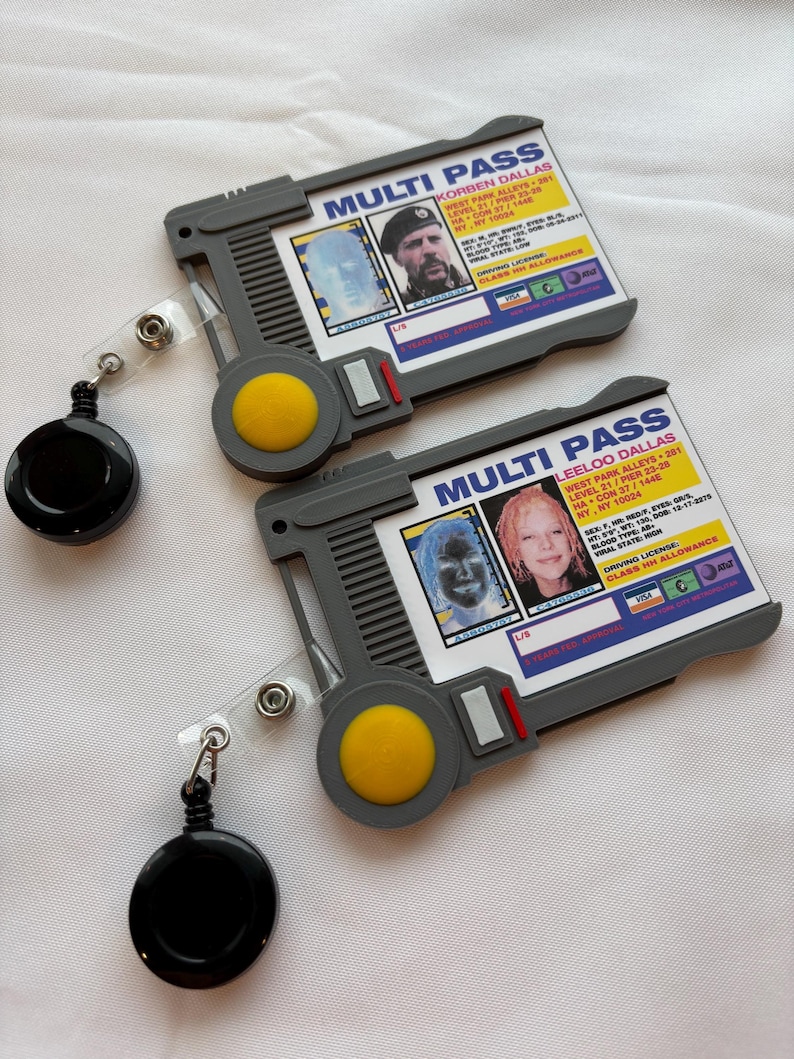 Puede incluir: Dos tarjetas multi-pass de pl&aacute;stico gris con fotos en blanco y negro de personas y texto que dice "MULTI PASS" y "KORBEN DALLAS" y "LEELOO DALLAS". Las tarjetas est&aacute;n unidas a carretes de identificaci&oacute;n retr&aacute;ctiles negros.