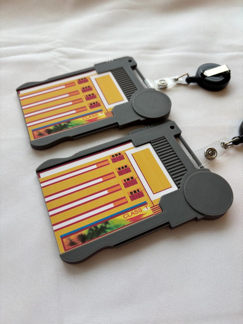 Puede incluir: Dos portagajetas de pl&aacute;stico gris con gr&aacute;ficos de barras amarillos y rojos y el texto "CLASS T" en la parte delantera. Cada portagajetas tiene un carrete de gajeta retr&aacute;ctil.