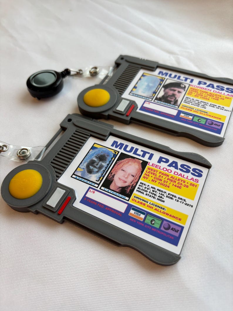 Puede incluir: Dos tarjetas multi-pass de pl&aacute;stico gris con un bot&oacute;n amarillo y un cord&oacute;n retr&aacute;ctil. Las tarjetas muestran una foto de una persona y texto que incluye "MULTI PASS", "KORBEN DALLASS", "LEELOO DALLAS", "CLASS HH ALLOWANCE" y "VISA".