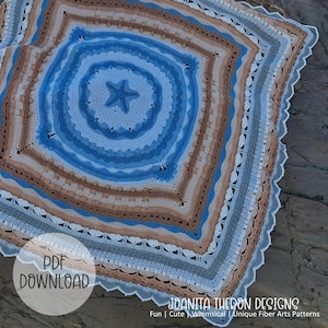 Puede incluir: Una manta cuadrada de ganchillo con un motivo central de estrella de mar azul rodeado de patrones circulares y cuadrados concéntricos en tonos azul, beige, blanco y gris. Los bordes están terminados con un delicado diseño de encaje festoneado.