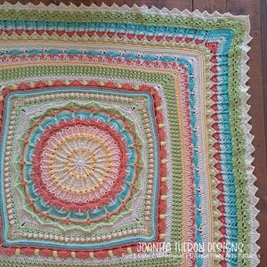 May include: A square, handmade crochet blanket in a variety of pastel colors, including peach, teal, yellow, and green. The blanket features intricate patterns and textures, with a scalloped edge. The text "JOANITA TULON DESIGNS" is visible in the bottom right corner.