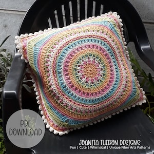 Op de afbeelding: Een kleurrijk gehaakt kussen met een mandala-ontwerp in tinten roze, oranje, groen, blauw en wit. Het kussen heeft een witte gehaakte rand met kleine witte pompoentjes. De tekst "PDF DOWNLOAD" en "JOANITA THERON DESIGNS" is zichtbaar in de afbeelding.