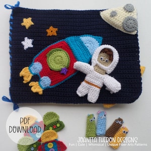 Puede incluir: Una manta de bebé tejida a crochet con un cohete, un astronauta y estrellas. La manta es azul con estrellas blancas y una luna amarilla. El cohete es rojo, azul y amarillo. El astronauta es blanco con una cabeza marrón. La manta está atada con cintas azules.