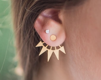 May include: Gold ear cuff with a geometric sunburst design. The ear cuff is worn with a small gold circle stud and a small diamond stud.