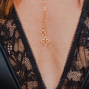 May include: A gold necklace with a delicate chain and a small, sparkling four-leaf clover pendant.