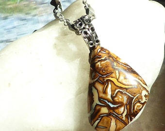 May include: A teardrop-shaped boulder opal pendant featuring a polished surface with swirling patterns of brown, cream, and iridescent blue, suspended from a silver-toned metal chain with a decorative filigree bail at the top of the stone.
