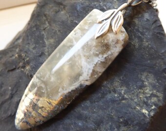 May include: A pendant featuring a long, tapered, semi-translucent stone with white veining and a metallic, bronze-colored base. The top of the stone is capped with a silver-toned metal bail shaped like two small leaves, attached to a silver chain.