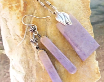 May include: A jewelry set featuring a silver necklace with a pendant, and matching earrings. The pendant and earrings have a rectangular, lavender-colored stone. The necklace chain and earring hooks are silver.
