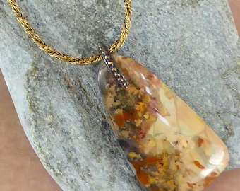 May include: A pendant necklace featuring a polished, irregular, translucent stone with inclusions of orange, brown, and cream colors. The stone is secured by a dark metal bail and hangs from a gold-toned, twisted rope chain necklace.