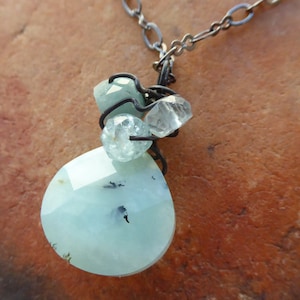 May include: A silver chain necklace with a light blue teardrop-shaped pendant and smaller clear and light blue crystals.