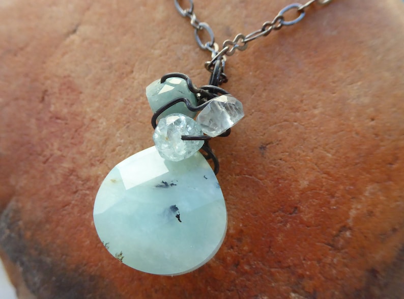 May include: A silver chain necklace with a light blue teardrop-shaped pendant and smaller clear and light blue crystals.
