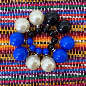 May include: A set of double-sided earrings with a variety of colors, including white, black, and blue. The earrings are made of round beads and are arranged in a circle.