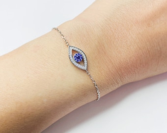 Puede incluir: Una pulsera de plata con un dije azul de ojo turco. El dije está rodeado de pequeñas piedras transparentes.