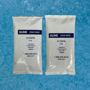 May include: Two white ULINE cold packs, each with the text "COLD PACK", "S-13376", and "3 oz.". The packs also state they are leak proof, colder than ice, non-toxic, and reusable. The background is a light blue.