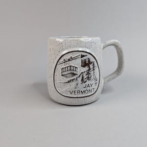 May include: White ceramic mug with a brown graphic of a ski lift and the text "Jay Vermont".