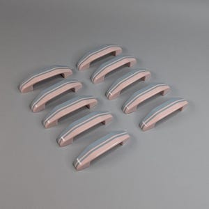 May include: Ten pink cabinet handles with two light blue stripes are displayed. The handles have a curved design and are arranged on a grey background. These handles are suitable for kitchen or bathroom cabinets.