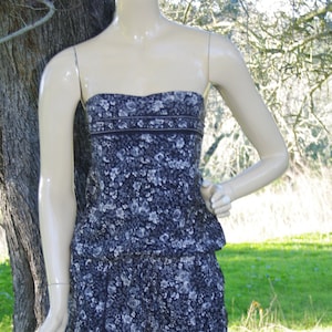 Peut inclure: Une combinaison sans bretelles à imprimé floral noir et blanc avec un corsage ajusté et un bas ample et fluide.