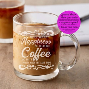 May include: A clear glass coffee mug with a white design that reads "Money can't buy happiness but it can buy coffee and that's pretty much the same thing".