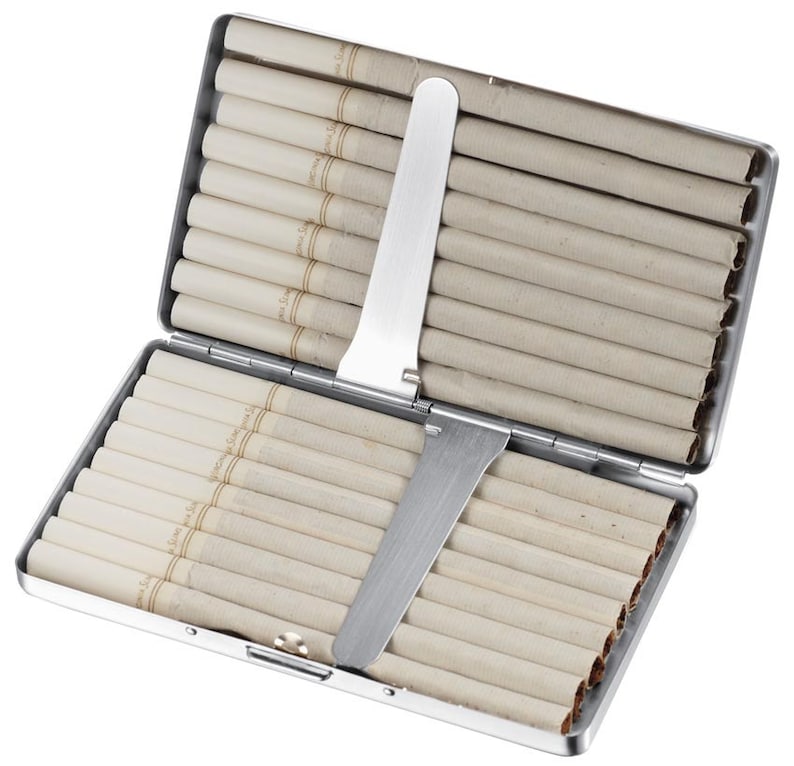May include: A silver cigarette case with a metal slide to push cigarettes out. The case is open and filled with white cigarettes.
