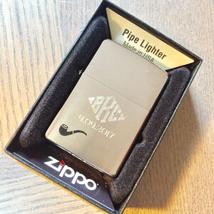 May include: A silver Zippo lighter with a personalized engraving of a monogram and the date 9.09.2017. The lighter is in a black box with the words "Pipe Lighter" and "Made in USA" printed on the top.