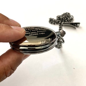 May include: A black pocket watch with a silver chain. The watch face is engraved with the text "09.11.2021 My heart you are my twin brother Love you forever Mama Olga"