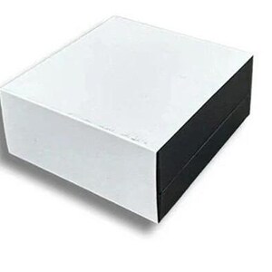 May include: A white square box with a black lid. The box is made of cardboard and has a smooth surface.