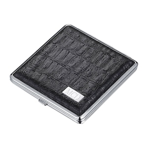 May include: A black leather cigarette case with a silver metal frame and the initials "MCD" embossed on the front.