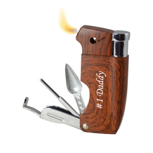 May include: A brown wood-grain multi-tool lighter with a built-in poker, tamper, and a scoop. The lighter has a flame and the tool is partially extended. The lighter is engraved with the text "#1 Daddy".