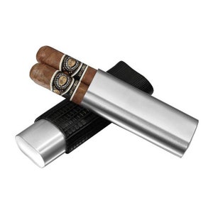 May include: A silver cigar tube with a black leather sleeve. The tube is open and two cigars are inside. The cigars are labeled "1897 Anniversary"