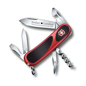 May include: A red and black Swiss Army knife with a personalized inscription that reads "Jordan ♥ Lyndsay Our first anniversary 05-04-2020". The knife has a variety of tools, including a blade, a corkscrew, a bottle opener, and a screwdriver.