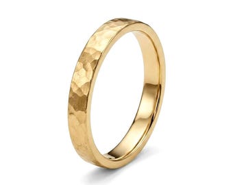 May include: A gold ring featuring a hammered texture on the outer surface. The band has a polished finish on the interior and edges, creating a reflective appearance. The metal surface displays irregular indentations across the entire exterior.