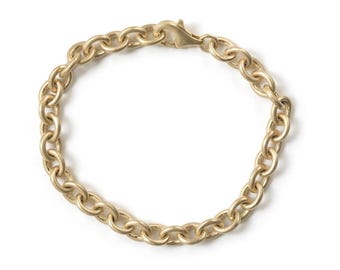 May include: A gold-toned chain bracelet featuring a series of uniform, rounded oval links connected in a continuous loop. The bracelet is secured with a polished lobster claw clasp mechanism that connects the two ends of the circular chain design.