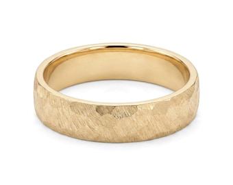 May include: A gold band ring featuring a textured, hammered exterior surface and a smooth, polished interior. The metal has a warm yellow tone with a matte finish on the outer band, creating a distinct contrast against the reflective inner surface.