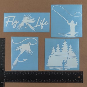Puede incluir: Cuatro calcoman&iacute;as de vinilo blanco sobre un fondo azul. Las calcoman&iacute;as presentan temas de pesca con mosca. Una calcoman&iacute;a dice "Fly Life" con un se&ntilde;uelo de pesca con mosca. Otra calcoman&iacute;a muestra una silueta de una persona pescando con mosca. La tercera calcoman&iacute;a muestra un se&ntilde;uelo de pesca con mosca. La cuarta calcoman&iacute;a muestra una silueta de una persona pescando con mosca frente a una l&iacute;nea de &aacute;rboles.