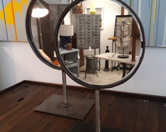 Vintage industrial salvaged cast iron wheel frame mirrors on a stand.