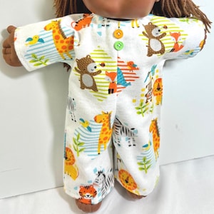 May include: A white doll pajamas with a button closure and a colorful animal print featuring zebras, giraffes, lions, tigers, bears, and birds.