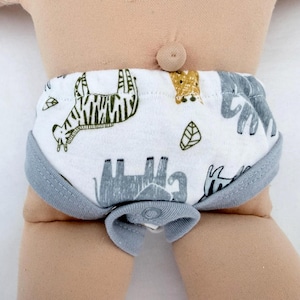 May include: A pair of white baby underwear featuring a repeating pattern of green zebras, gray elephants, and small leaves. The garment has solid gray trim along the leg openings and a single snap closure at the center front of the waistband.