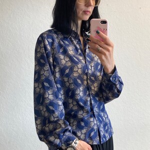 Pu&ograve; includere: Una camicia a maniche lunghe blu e oro con motivo, chiusura con bottoni e vestibilit&agrave; rilassata.